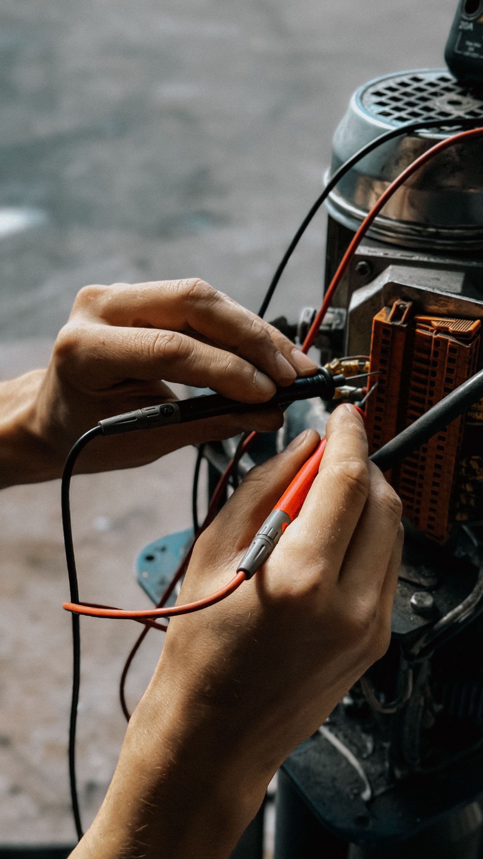 Close-up of hands using multimeter on motor wires. Precision in electrical testing.